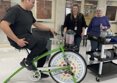 Teacher riding a bike that makes smoothies in an attached blender.